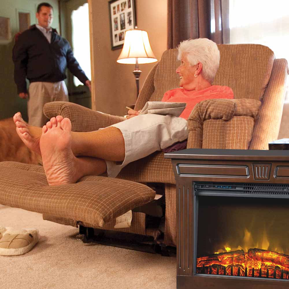 A woman relaxing in her easy-chair with an Amish Fireplace next to her