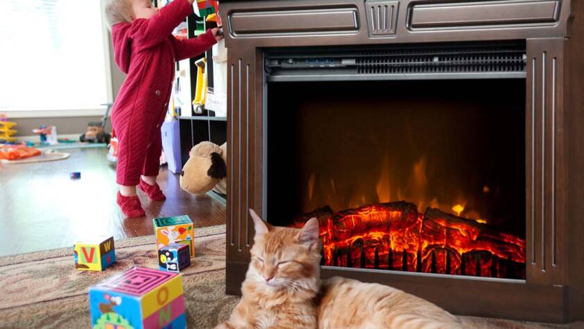 Cat resting near a Heat-n-Glow with a toddler playing in the background