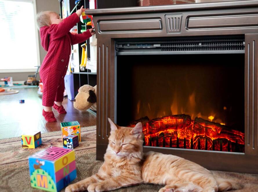 Cat resting near a Heat-n-Glow with a toddler playing in the background